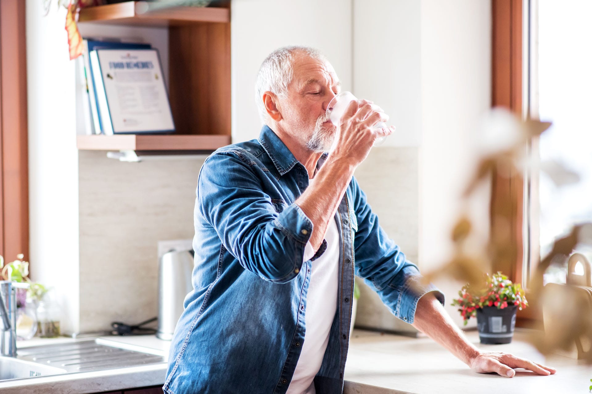 Senior Man In The Kitchen. An Old Man Inside The House, Drinking
