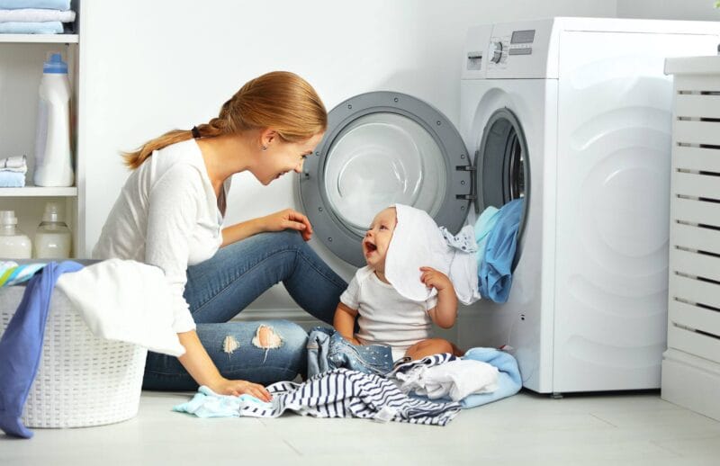Mother playing with child near washer