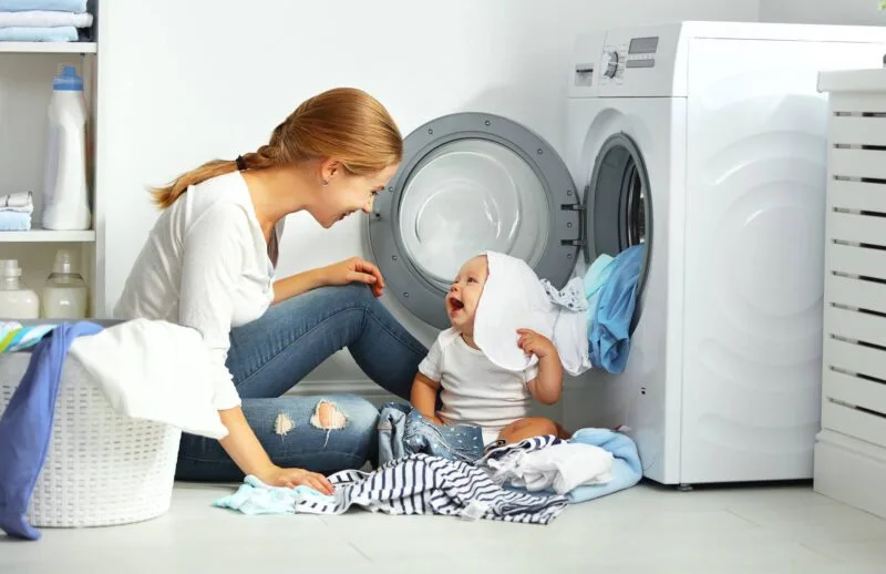 Mother playing with child near washer